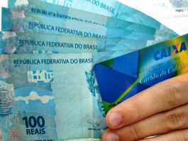 mão segura cartão cidadão e cinco cédulas de 100 reais