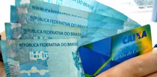 mão segura cartão cidadão e cinco cédulas de 100 reais