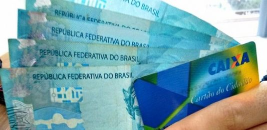 mão segura cartão cidadão e cinco cédulas de 100 reais