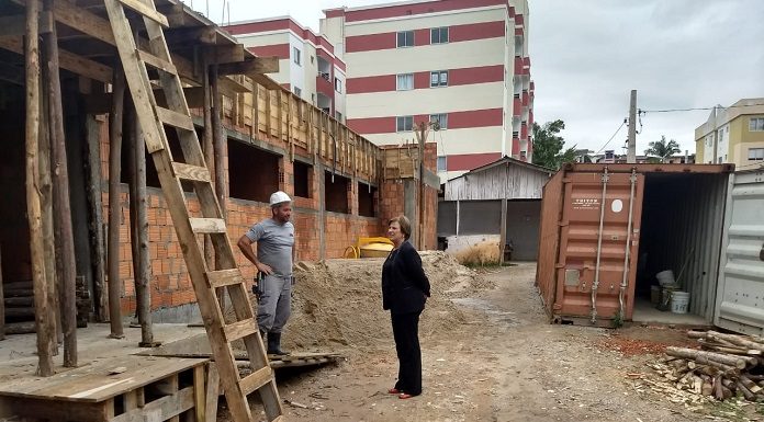ao lado de prédio em construção, prefeita adeliana conversa com um operário, usando capacete