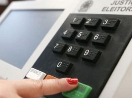 mão feminina aperta a tecla confirma da urna eeletrônica