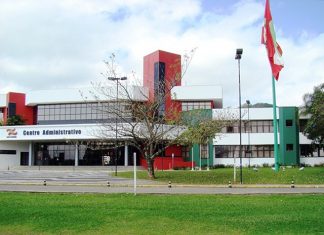 fodo do prédio sede do governo, com gramados e árvores na frente e a bandeira de sc