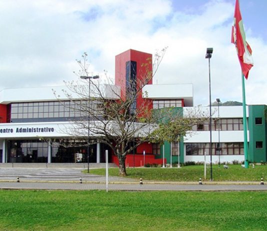 fodo do prédio sede do governo, com gramados e árvores na frente e a bandeira de sc