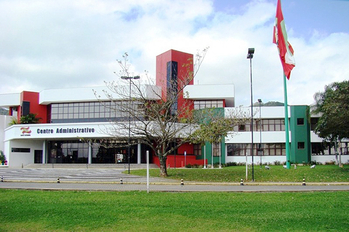fodo do prédio sede do governo, com gramados e árvores na frente e a bandeira de sc