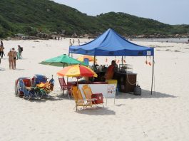 homem sobre tenda de bebidas instalada em praia de palhoça