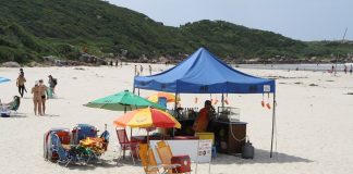 homem sobre tenda de bebidas instalada em praia de palhoça