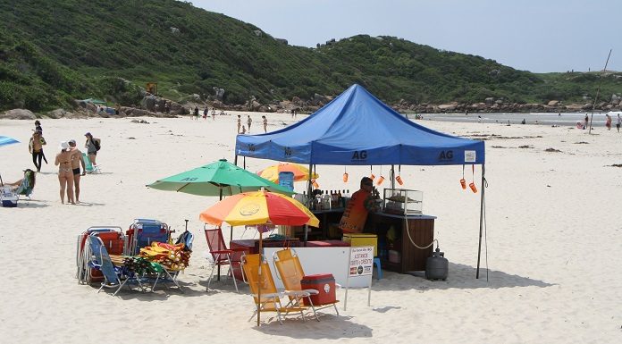 homem sobre tenda de bebidas instalada em praia de palhoça
