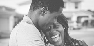 homem e mulher negra se abraçam sorridentes em foto preto e branco