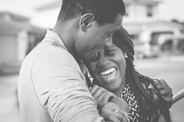 homem e mulher negra se abraçam sorridentes em foto preto e branco