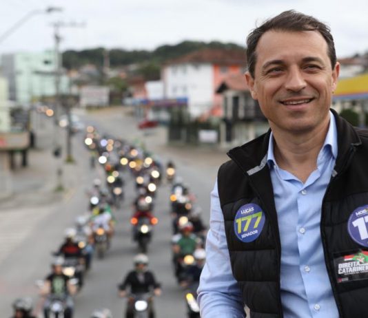 Comandante Moisés é eleito governador de Santa Catarina foto de moisés em cima de um caminhão, usando colete e adesivos do partido; há uma fila de motos que o acompanhando ao fundo na rua