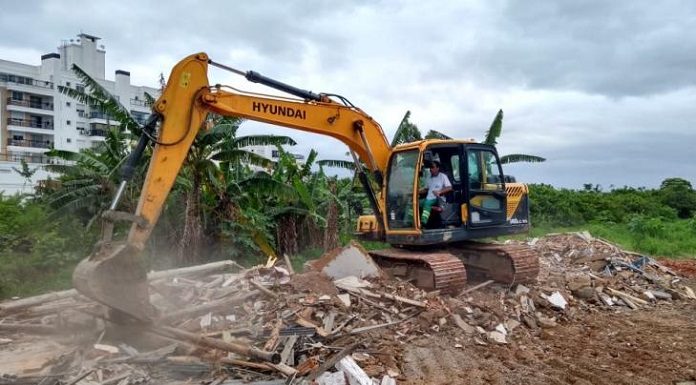 operário em retroescavadeira sobre escombros em área do parque