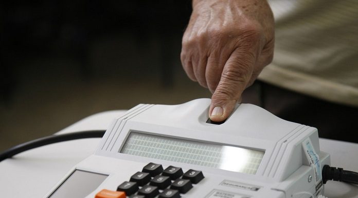 pessoa coloca o dedo para ser lido por leitor biométrico de votação