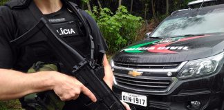 policial civil segurando metralhadora em frente a uma caminhonete da corporação