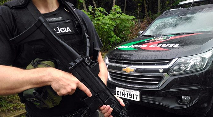 policial civil segurando metralhadora em frente a uma caminhonete da corporação