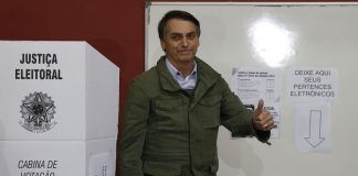 bolsonaro faz sinal de positivo ao lado de cabine eleitoral