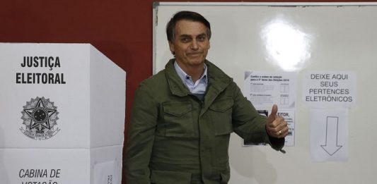 Jair Bolsonaro é eleito presidente do Brasil bolsonaro faz sinal de positivo ao lado de cabine eleitoral