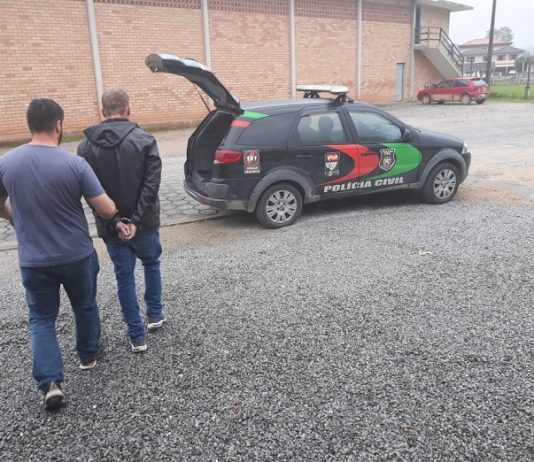 policial leva homem algemado em direção a viatura