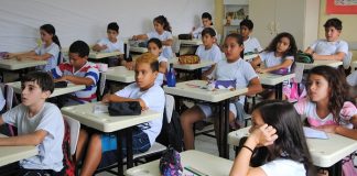 crianças sentadas em carteiras numa sala de aula