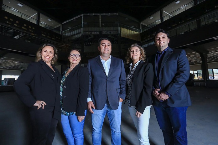 as cinco pessoas posam sorridentes para a foto dentro da arena