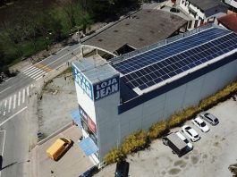 loja vista de cima, em foto de drone, mostrando todos os painéis solares no teto do prédio; há um logo "loja jean"