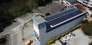 loja vista de cima, em foto de drone, mostrando todos os painéis solares no teto do prédio; há um logo "loja jean"