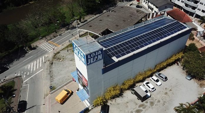loja vista de cima, em foto de drone, mostrando todos os painéis solares no teto do prédio; há um logo "loja jean"