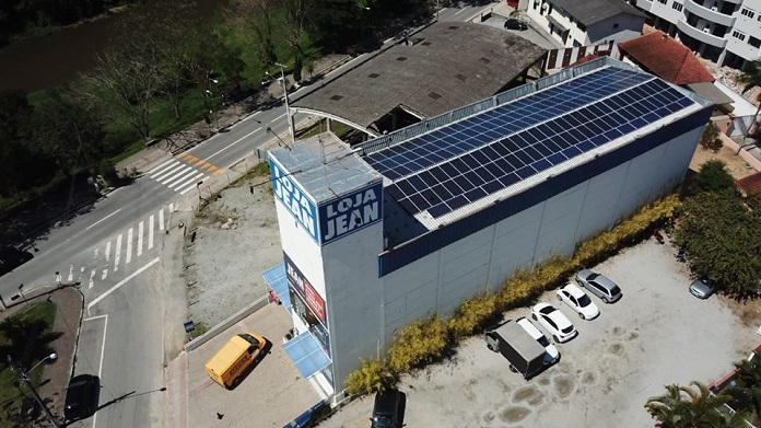 loja vista de cima, em foto de drone, mostrando todos os painéis solares no teto do prédio; há um logo 