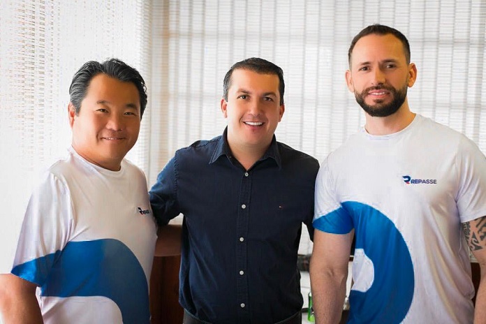 prefeito camilo posa para a foto com dois homens da empresa, usando camisas escritas 