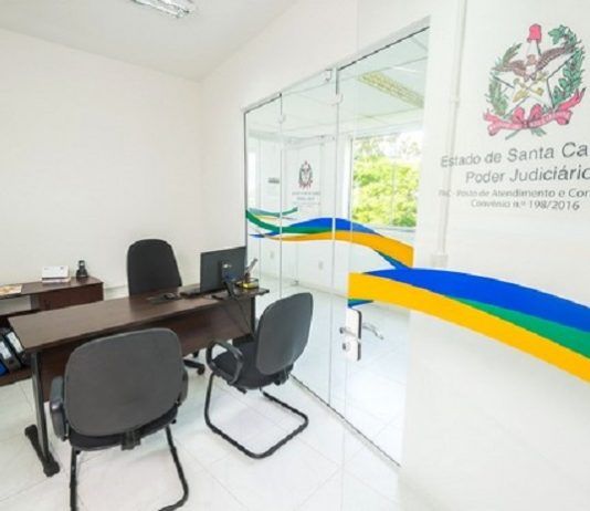 Aberta a Semana da Conciliação para resolução de dívidas em todo o Estado pequena sala de escritório com mesa e cadeiras e na parede o símbolo do tj