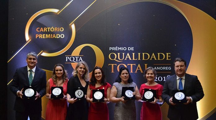 sete pessoas posam para a foto mostrando os troféus recebidos