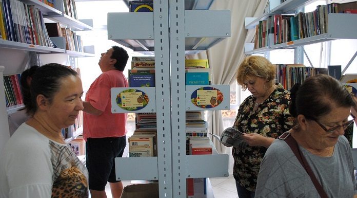 mulheres circulando entre prateleiras de biblioteca