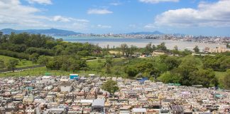 vista aérea do cemitério mostrando centenas de túmulos e jazigos; há uma área verde ao fundo e, mais longe, mar e montanha