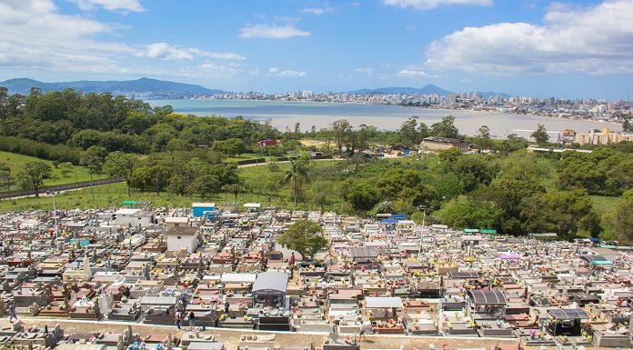 vista aérea do cemitério mostrando centenas de túmulos e jazigos; há uma área verde ao fundo e, mais longe, mar e montanha