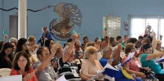 pessoas idosas sentadas na plateia com os braços levantados