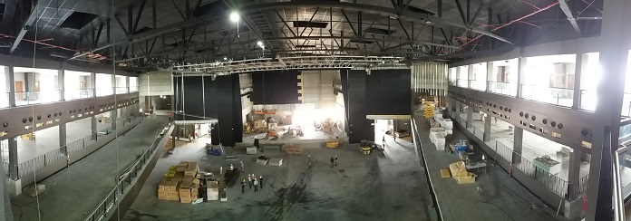 foto panorâmica do salão principal da arena, em época de construção, com operários
