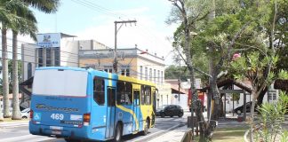 ônibus azul e amarelo parando em um ponto de ônibus em uma praça