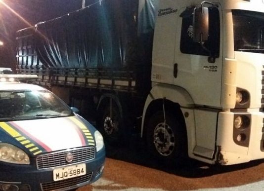 viatura da prf estacionada ao lado do caminhão de noite