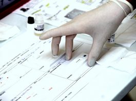 profissional usando luva coloca teste rápido em cima de uma tabela de papel