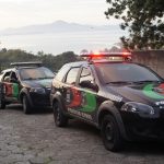 carros da polícia civil parados em uma ladeira e alguns policias andando na rua