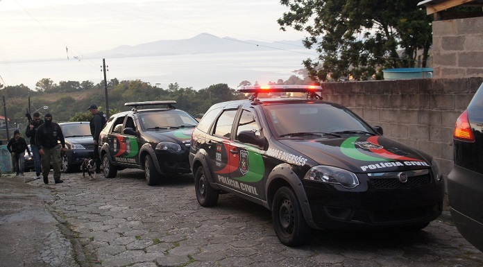 carros da polícia civil parados em uma ladeira e alguns policias andando na rua