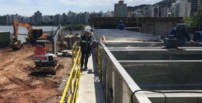 homem usando capacete de proteção anda por plataforma ao lado de obra