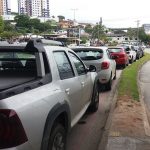 carros estacionados ao longo de uma rua e ao lado de uma ciclovia