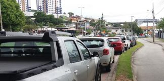 carros estacionados ao longo de uma rua e ao lado de uma ciclovia