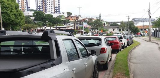 carros estacionados ao longo de uma rua e ao lado de uma ciclovia