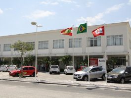 fachada do prédio da camara com alguns carros estacionados à frente e bandeiras hasteadas