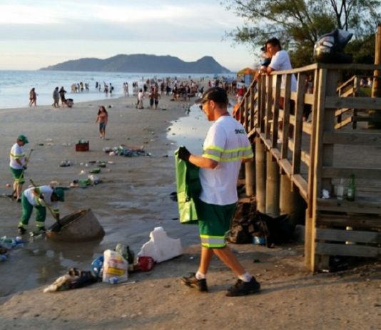 garis da comcap recolhendo muito lixo espalhado na praia do campeche, em florianópolis