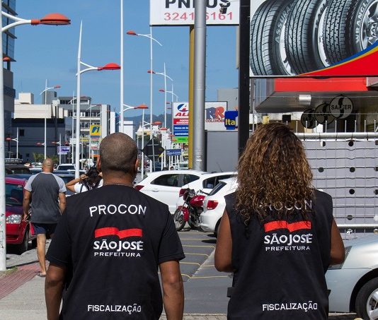 Confira dicas dos Procons para as compras de Natal dois agentes do proncons de são jose andando na rua com colete do órgão