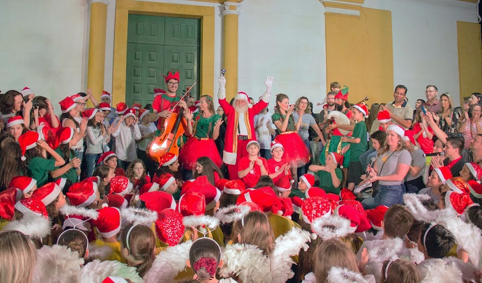 programacao de natal encerra nesta semana centro historico sao jose coral natalino vestido à caráter com um papai noel no meio com os braços pra cima em frente à igreja matriz de sj