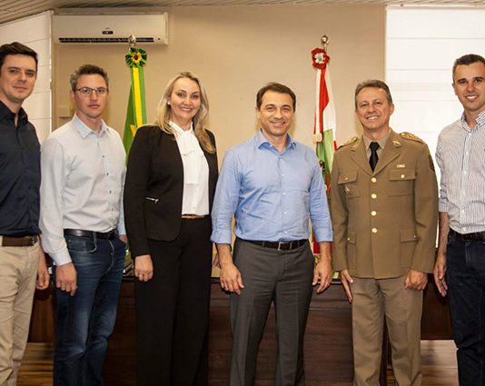 grupo posa sorridente para a foto em gabinete com bandeiras