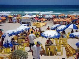 Até 7.500 temporários podem ser contratados neste Verão, estima Fecomércio dezenas de mesas e cadeiras com guarda-sóis espalhados por um praia e pessoas circulando